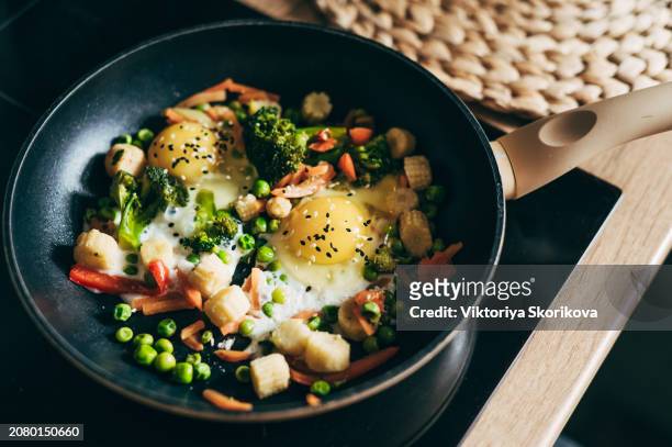 closeup of fried eggs and vegetables in a frying pan. - spinach frittata stock pictures, royalty-free photos & images