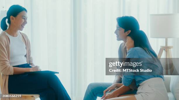 asian couples hug each other after consulting about relationships and mental health problems with a therapist. professional social worker assist married couples with empathy. - promises rehab center foto e immagini stock