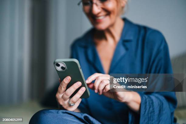 anonymous older woman holding and using mobile phone in bed - mobiltelefon bildbanksfoton och bilder
