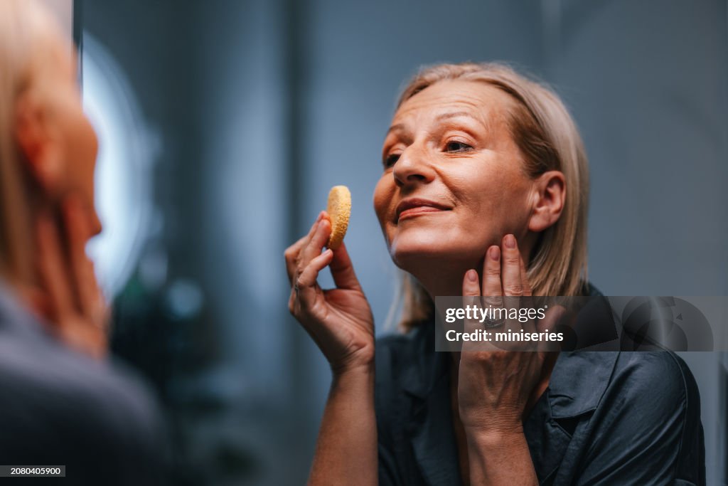 Portrait of a Beautiful Older Woman Using a Make up Sponge in the Bathroom