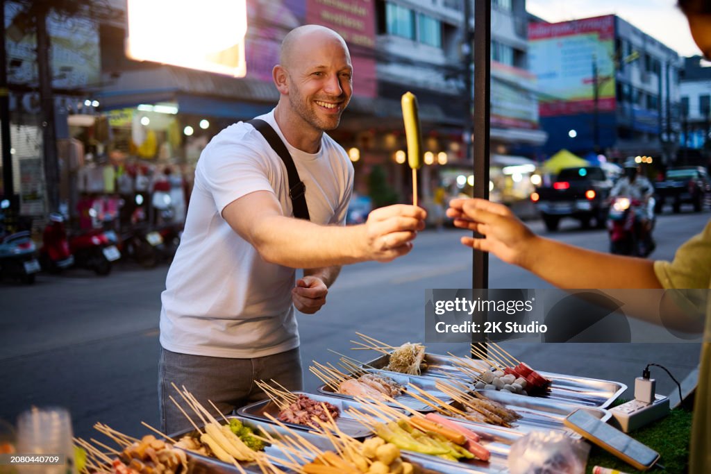 A man buys food at a night market in Thailand