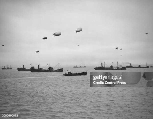Convoy of merchantmen and colliers protected by warships of the Royal Navy and anti aircraft barrage balloons assemble off the North West Coast of...