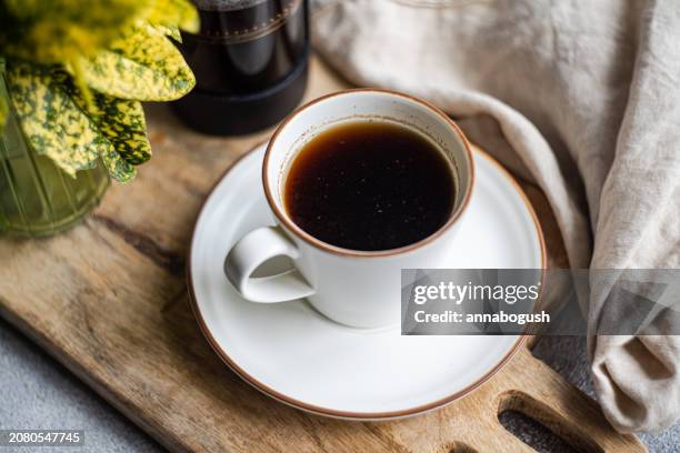close-up of a cup of black coffee on a chopping board with a cafetiere, napkin and foliage - black coffee stock pictures, royalty-free photos & images