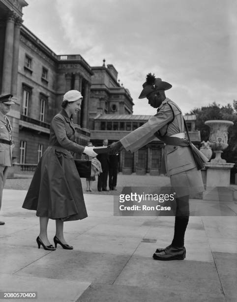 Warrant officer platoon commander Bugozi presents Queen Elizabeth II with a book on the history of the King's African Rifles Regiment at Buckingham...