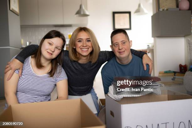 happy donation manager with her friends with down syndrome at home. - man holding donation box stock pictures, royalty-free photos & images