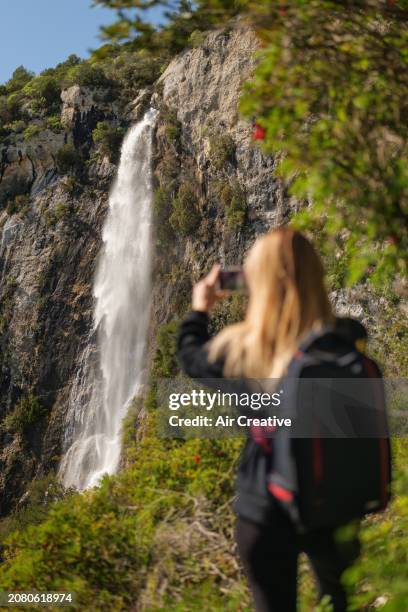 young adult woman hiker photographing a waterfall on a sunny day, alpes-maritimes, france - air france stock pictures, royalty-free photos & images