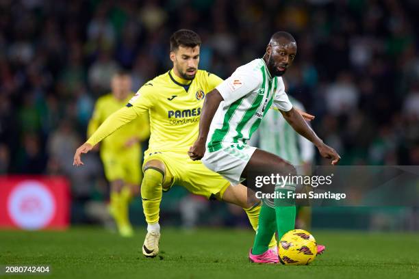 Youssouf Sabaly of Real Betis is challenged by Alex Baena of Villarreal CF during the LaLiga EA Sports match between Real Betis and Villarreal CF at...