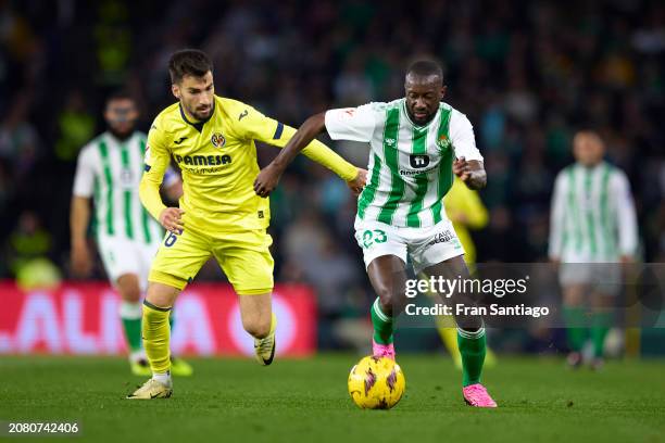 Youssouf Sabaly of Real Betis is challenged by Alex Baena of Villarreal CF during the LaLiga EA Sports match between Real Betis and Villarreal CF at...