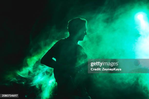 silhouette of a guitarist on stage light and smoke effects. - modern rock stock pictures, royalty-free photos & images