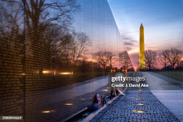 Sunrise is reflected in "The Wall" at the Vietnam Veterans Memorial on March 13 in Washington, DC. The Washington Monument is in the background.