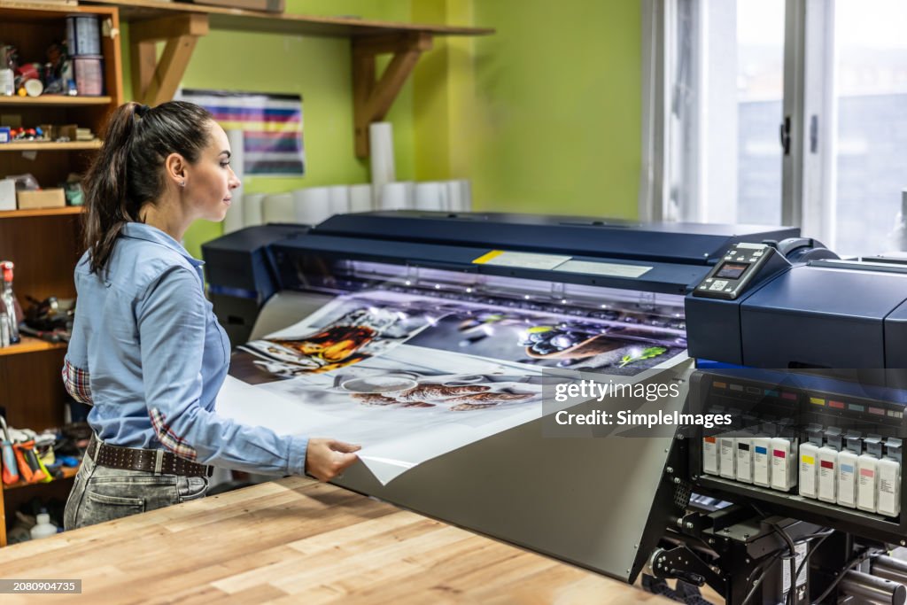 A woman manually checks the quality of a cmyk offset printer.