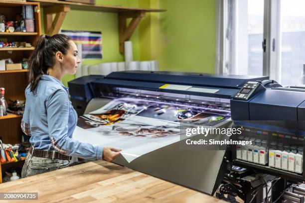 a woman manually checks the quality of a cmyk offset printer. - pressa da stampa foto e immagini stock