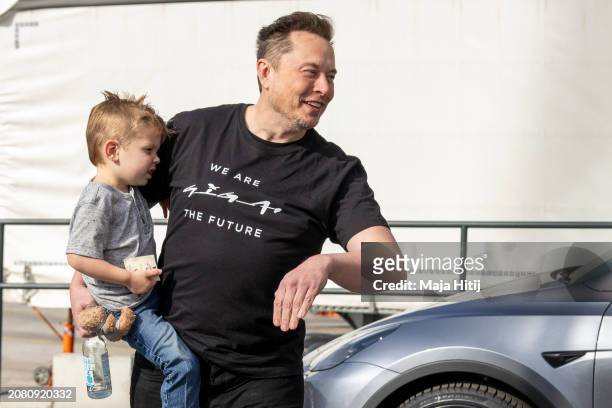 Tesla CEO Elon Musk leaves the Tesla Gigafactory electric car plant as he holds his son X Æ A-XII during a visit on March 13, 2024 near Gruenheide,...