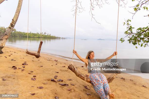 wild shore serenade: l'altalena di una giovane donna in mezzo alla tela della natura - fare laltalena foto e immagini stock