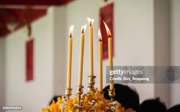 light candles in buddhist temple, thailand. they're often placed in front of buddhist shrines as a mark of respect or deference. - candlelight ceremony stock pictures, royalty-free photos & images