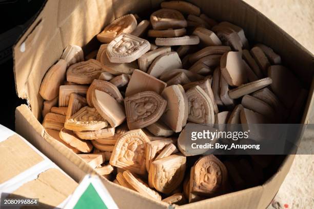 group of small terracotta buddha amulets containing in paper box. small buddha image used as amulet in thai culture. - trust god stock pictures, royalty-free photos & images