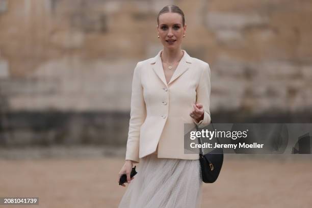 Guest is seen wearing a creme blazer, white long skirt, Dior black saddlebag outside Christian Dior during the Womenswear Fall/Winter 2024/2025 as...