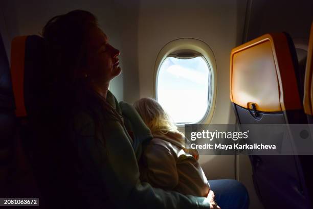 a mother breastfeeding her baby boy while traveling on airplane - travel stock pictures, royalty-free photos & images
