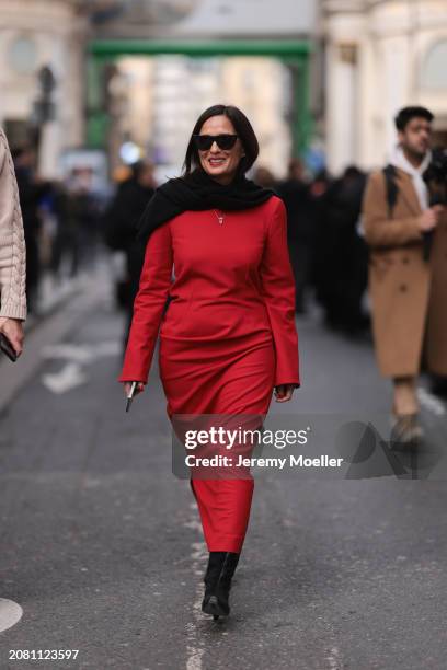 Guest is seen wearing a red long dress, black scarf, black leather boots and black sunglasses outside Dries Van Noten show during the Womenswear...