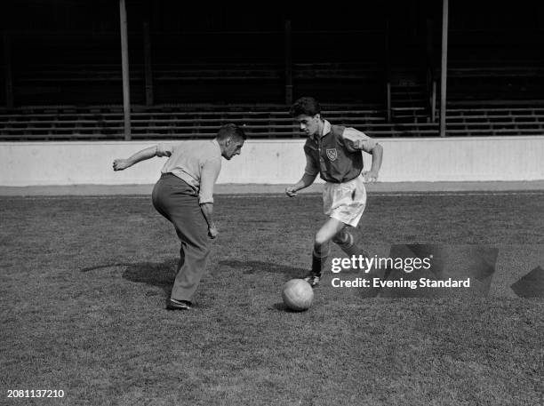 West Ham Football Club striker Harry Hooper Jnr dribbles a ball during training against his father, former footballer Harry Hooper Snr , September...