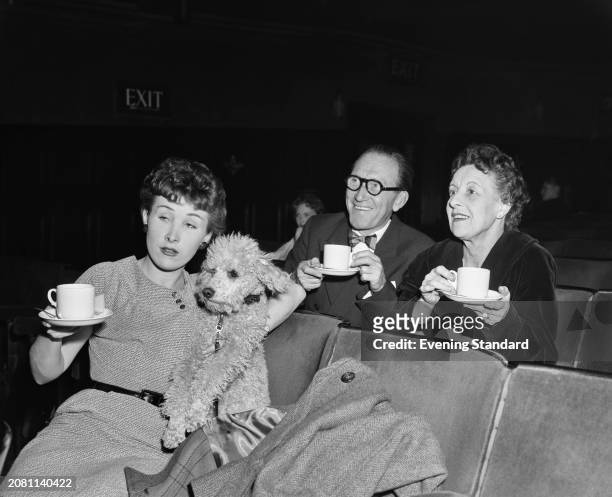 Actress Anthea Askey with her father, actor and comedian Arthur Askey and mother Elizabeth Askey holding tea cups while seated in an auditorium with...