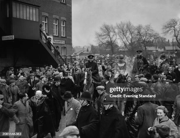 'Quare Times' ridden by jockey Pat Taaffe is led into the paddock surrounded by spectators and policemen after winning the Grand National horse race,...