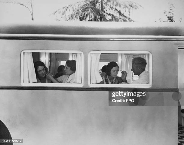 American actress and dancer Helen Cohan and Irish actress Maureen O'Sullivan both appear alongside make-up artists in the windows of a portable...