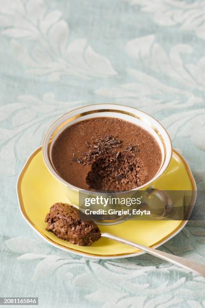 a yellow porcelain cup with mocha chocolate mousse on a light blue floral tablecloth - mousse stockfoto's en -beelden