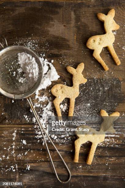 three festive christmas deer shaped cookie biscuits on a rustic board with icing sugar in a sifter - powdered sugar sifter fotografías e imágenes de stock