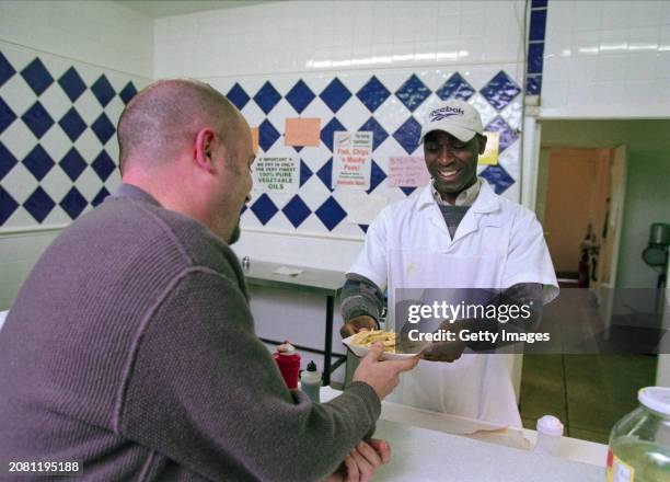 Manchester United striker Andy Cole pictured working in a Fish and Chip Shop during a Television commercial for Reebok sportswear in 1998.