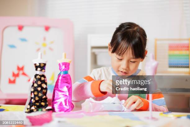 young girl was designing dress for doll  at home - doll house stockfoto's en -beelden