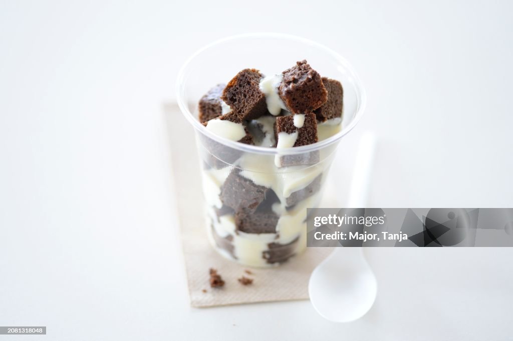 Brownies with vanilla sauce in a takeaway cup