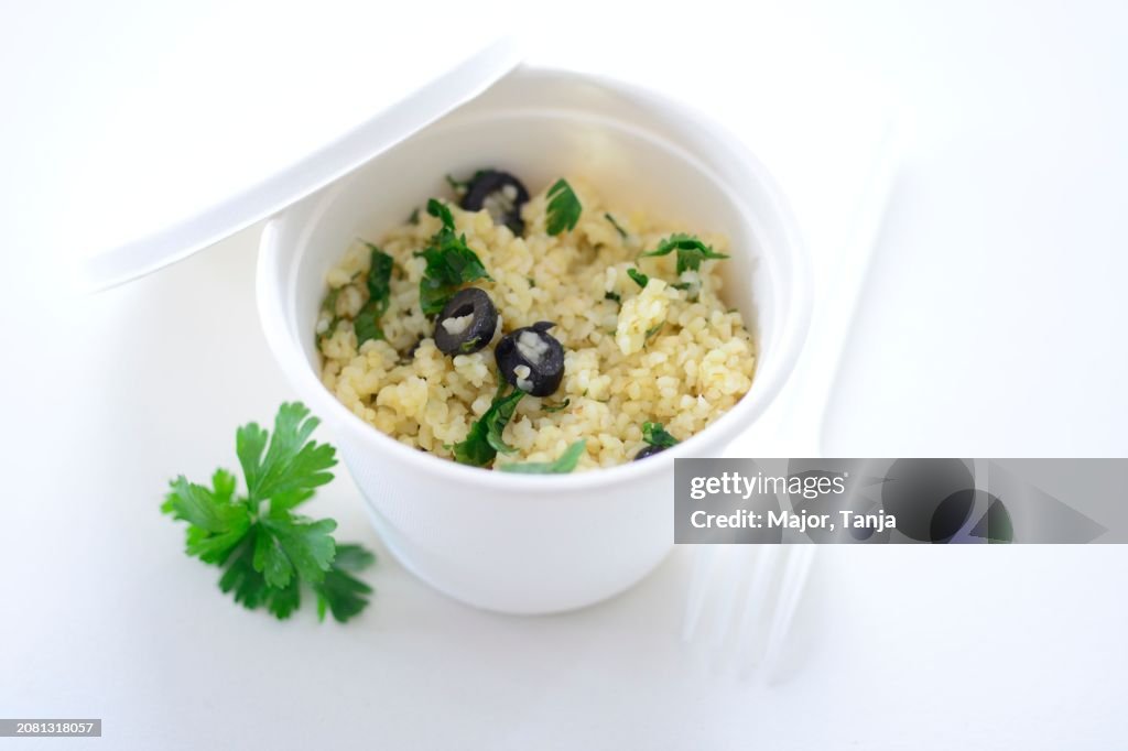 Couscous with olives and parsley in a takeaway cup