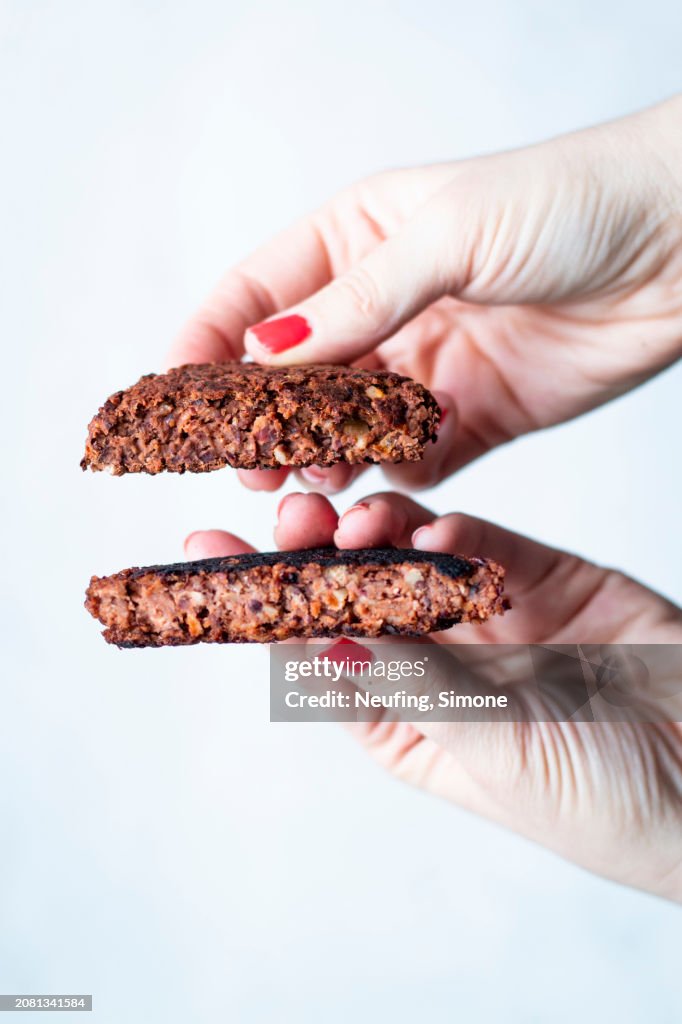 Hands holding a vegetarian burger pattie made from black beans