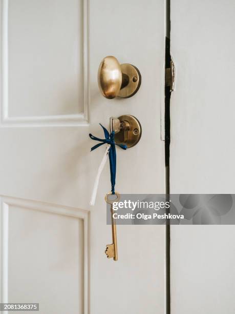 vintage key hanging on a brass door knob, symbolizing security and home entrance - latch stock pictures, royalty-free photos & images