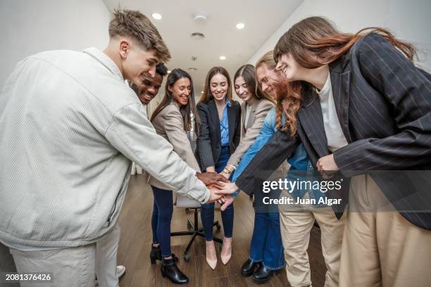 united effort: office team joins hands in a show of solidarity and cooperation - alleanza foto e immagini stock