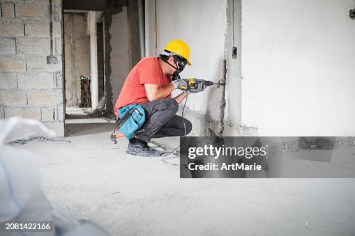 Worker using hammer drill at a construction site Worker using hammer drill at a construction site