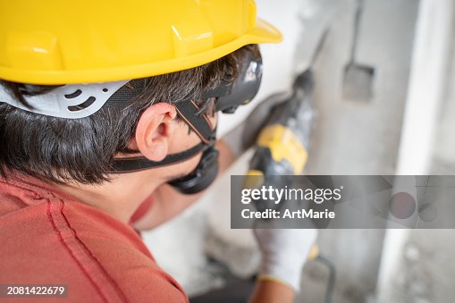 Worker using hammer drill at a construction site Worker using hammer drill at a construction site