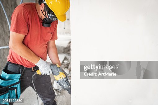 Worker using hammer drill at a construction site Worker using hammer drill at a construction site