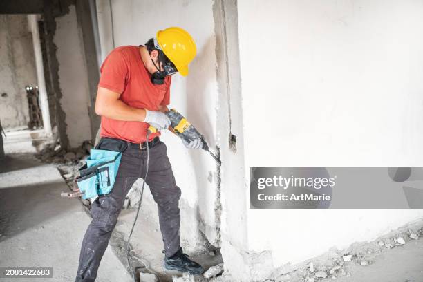 arbeiter mit bohrhammer auf einer baustelle - presslufthammer stock-fotos und bilder