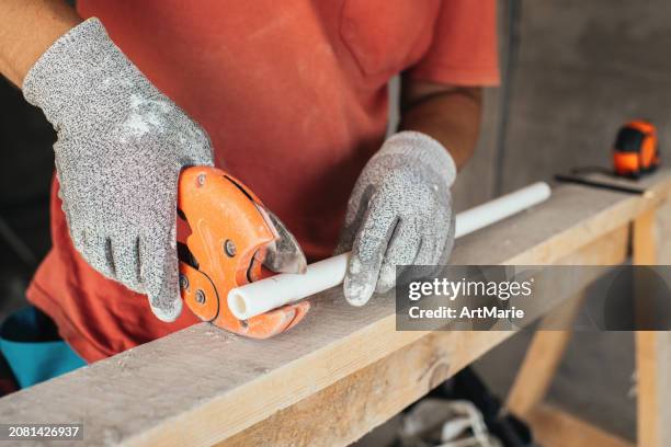 trabajador de la construcción cortando tubería de pvc durante la renovación en un sitio de construcción - pvc fotografías e imágenes de stock