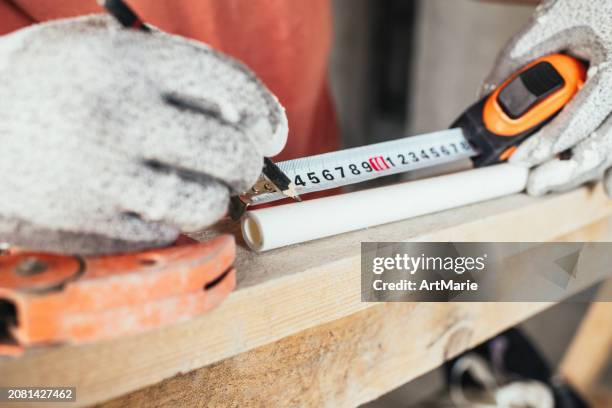 construction worker measuring pvc pipe during reconstruction/renovation at a construction site - agricultural-machinery-repairs stock pictures, royalty-free photos & images