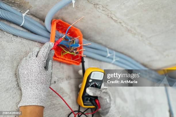 electrician testing voltage at a construction site during home or apartment renovation, repair or reconstruction - electrical panel box fotografías e imágenes de stock