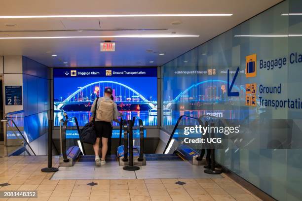 Bloomington, Minnesota. MSP airport. Travelers taking the escalator down to the baggage and ground transportation area.