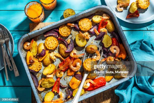 baked vegetables with shrimps (corn, red onion, peppers, potatoes) - baking sheet stock pictures, royalty-free photos & images
