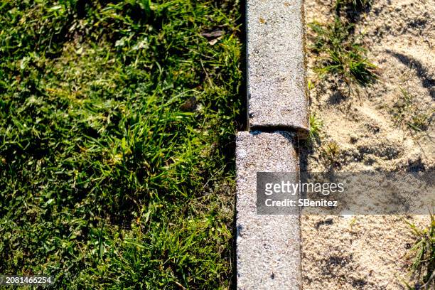 separation by an uneven curb of a grass area with another sand area - surfacing stock pictures, royalty-free photos & images