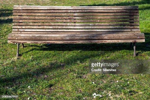 a rather deteriorated park bench on a floor with grass and daisies - surfacing stock pictures, royalty-free photos & images