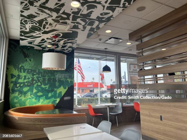 Interior of a McDonald's restaurant showing modern seating and decor with natural lighting and American flag visible outside, Lakewood Boulevard,...