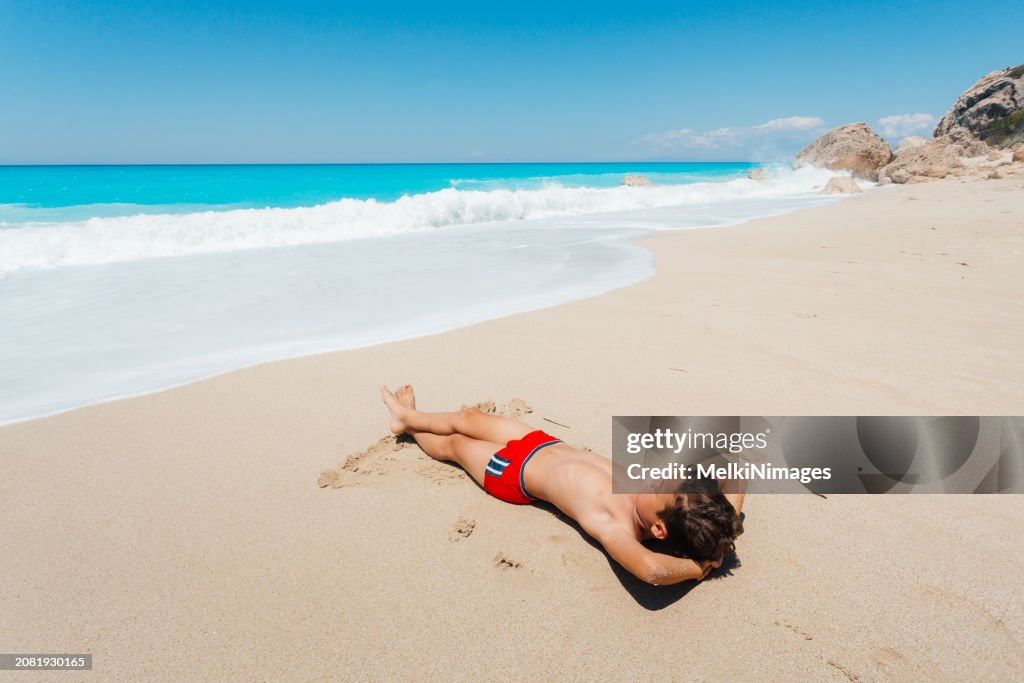 Bot Sunbaking Boy Enjoys Sunbathing On The Beach High-Res Stock Photo - Getty Images