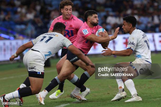 Waratahs' Triston Reilly avoids a tackle by Blues' Caleb Clarke and Stephen Perofeta during the Super Rugby match between the NSW Waratahs and the...